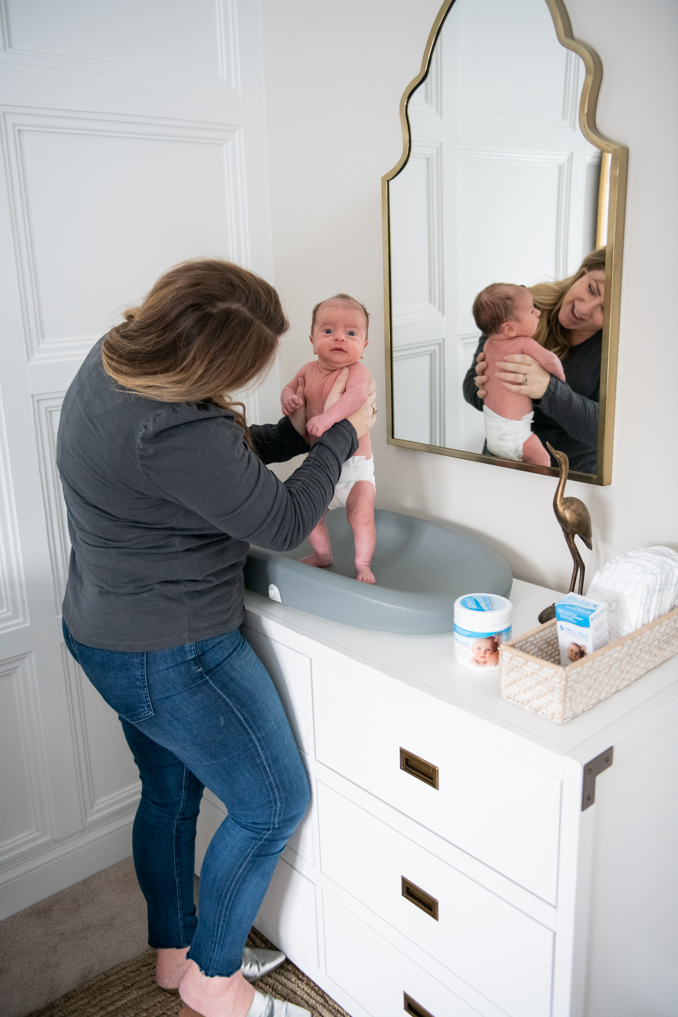 Diaper Rash Remedies by popular Ohio motherhood blog, Coffee Beans and Bobby Pins: image of a mom holding her baby boy on a grey changing pad on a white dresser. 