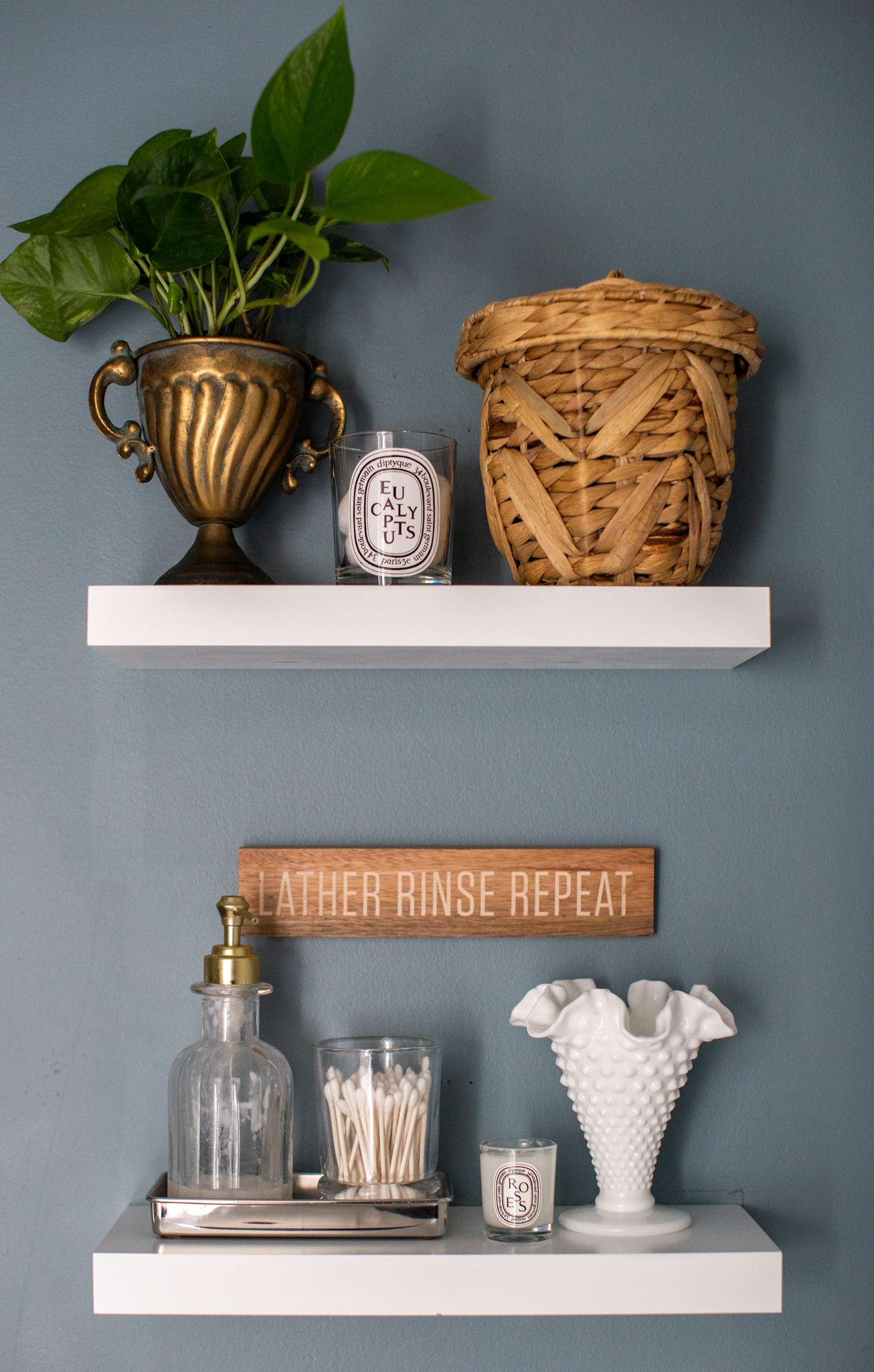 Guest Bathroom Makeover by popular Ohio life and style blog, Coffee Beans and Bobby Pins: image of white floating shelves decorated with a plant, seagrass basket, milk glass vase and candle, and a while vanity. 